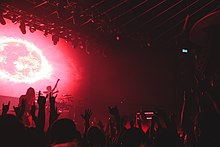 Gojira onstage under red lights, seen from the audience