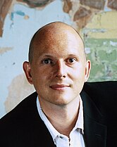 A bald middle-aged man looking into the camera.