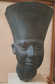 Black statue of a head wearing a large crown