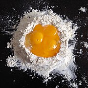 Eggs are cracked into a well of flour