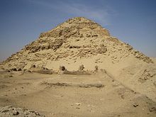Ruins of a pyramid, its shape well preserved, in the desert