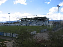 Vue d'un terrain de football bordé d'une tribune au-dessus de laquelle on lit « Colmar Stadium ».