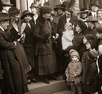 3 well-dressed women stand on courthouse steps, surrounded by a crowd of supporters.