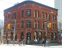 Three-storey building clad in red bricks and a downtown street scene