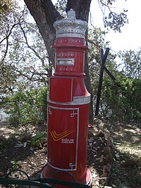 Tall, round red mailbox with decorative crown on top