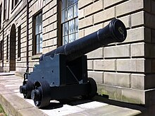 A cannon from the Chesapeake positioned next to a brick wall