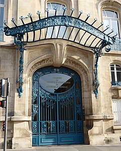 Art Nouveau metal and glass door in Nancy (France), with a big transparent awning above it