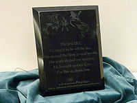 A plaque dedicated to Gary Gygax at Gen Con 2008 reading: "The first DM, He taught us to roll the dice. He opened the door to new worlds. His work shaped our industry. He brought us Gen Con, For this we thank him. In fond memory of Gary Gygax and in celebration of his spirit and accomplishments."