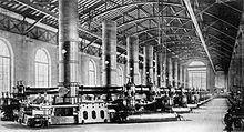 Vieille photo en noir et blanc d'une hall industrielle toute en longueur.