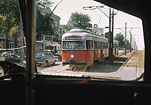 A streetcar at a small platform in the median of an urban street