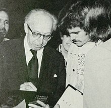 Man wearing glasses and a suit on the left next to another man