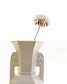 Aged ceramic white vase holding a chrysanthemum