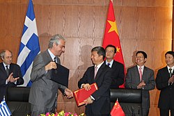 2011년 5월 17일 당시 그리스 국제외교위원회 부위원장이었던 스피로스 쿠벨리스(사진 앞 왼쪽)와 아울러 서로 수교 서류에 서명하고 상호 악수를 나누는 쑹타오(사진 앞 한가운데 붉은색 서류철을 들고 있는 이가 쑹타오 당시 중국공산당 중앙대외연락부 차장)