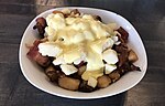 A breakfast poutine with hollandaise sauce and bacon.