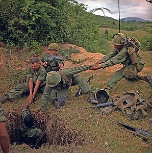 An infantryman is lowered into a tunnel by members of a reconnaissance platoon during Operation Oregon of the Vietnam War