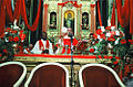 O altar e o Padre Dalton Caram durante a Festa do Divino Espírito Santo, enfeitado com veludo vermelho, por ser a cor que representa o Espírito Santo