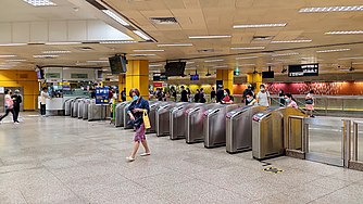 Concourse level with fare gates dividing the unpaid and paid areas of the station. A rainbow dressing of 15,000 coloured tiles is displayed along the concourse in the background.