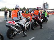 Orange high-visibility tabards worn by competitive motorcyclists