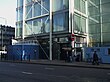 A building covered in windows with a blue sign reading "EUSTON SQUARE STATION" in white letters all under a blue sky with white clouds