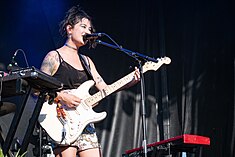 Michelle Zauner playing guitar and smiling into a microphone