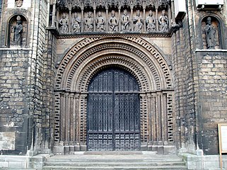 The mouldings of the arched central west door of Lincoln Cathedral are decorated by chevrons and other formal and figurative ornament typical of English Norman. The "Gallery of Kings" above the portal is Gothic