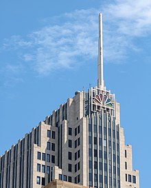 Closeup of the top of an Art Deco-styled skyscraper with the NBC peacock logo