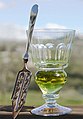 Image 26A reservoir glass filled with a naturally colored verte absinthe, next to an absinthe spoon (from List of alcoholic drinks)