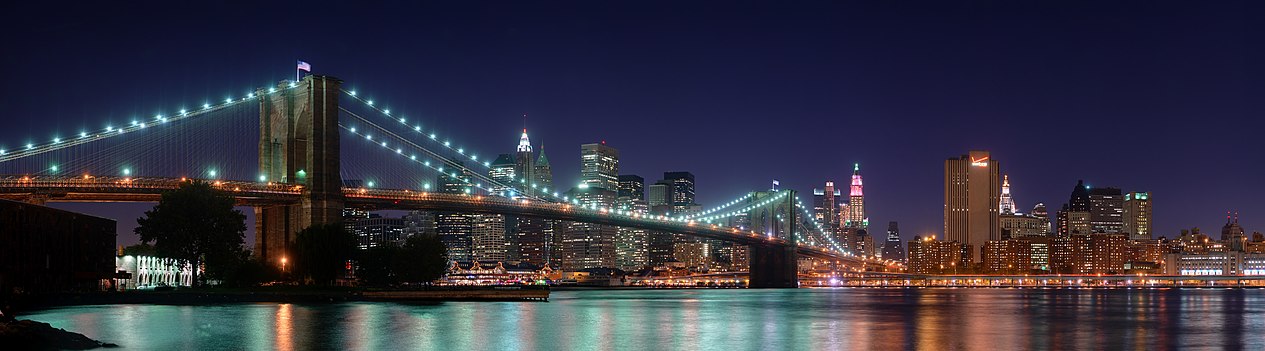 Panorama visutého Brooklynského mostu přes řeku East River s mrakodrapy Finančního distriktu na newyorském Manhattanu