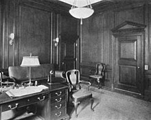 Photograph of J.P. Morgan's wood-paneled office with a desk, several chairs and a sofa