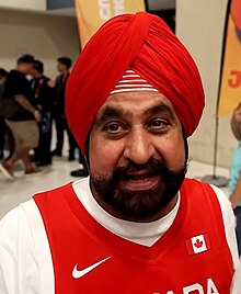 Portrait photograph of Bhatia wearing red at the Serbia vs. Canada 2023 FIBA Basketball World Cup game
