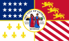 Quartered flag. Top left: blue with 17 white stars. Top right: Red with 3 golden lions. Bottom left: White with 5 gold fleur-de-lis. Bottom right: 13 alternating white and red stripes, diagonally downward. Center is covered by the city seal in color