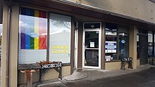 Photograph of the restaurant's exterior, featuring a rainbow flag, sign saying "We serve dinner brunch", an open sign, and quote signs, all next to the entrance
