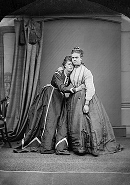 Park and Boulton hug, both wearing Victorian ladies dresses