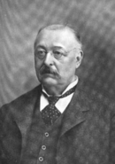 picture of a formally dressed man with little hair and a mustache