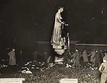 Black and white photograph of students dancing around the Statue of Industry after tarring it