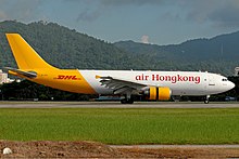 An aircraft painted in white colour with the name Air Hong Kong painted in red on the fuselage, and in yellow colour from the rear to the tail with the name DHL painted in red on the tailfin.