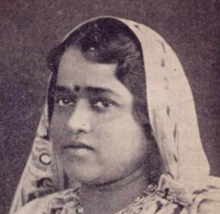 A South Asian woman with a bindi; her dark waved hair is partly covered by a light-colored dupatta