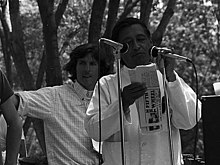 Cesar Chavez holding a newspaper in front of a microphone