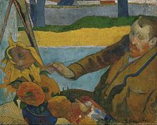 Kahverengi palto giymiş kızıl sakallı adam, sola doğru bakıyor, sağ elinde resim fırçası var ve büyük ayçiçekleri resmini yapıyor.
