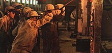 A group of workers inside a steel manufacturing facility