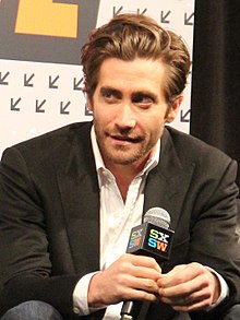 Photo of Jake Gyllenhaal sitting while holding a microphone