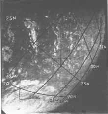 Black and white satellite image of a hurricane with an eye and well organised structure. Due to the storm's position near the edge of the image, most of the hurricane is not visible. The curvature of the Earth is visible on the right, and a coordinate grid with labels has been superimposed on the image.
