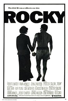 In a black-and-white poster, Rocky in his boxing outfit holding hands with another person. The tagline above the film's title reads "His whole life was a million-to-one shot." The film's credits are printed below the poster.