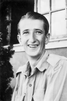 A black and white head and shoulders portrait of a young man wearing a uniform shirt and looking into the camera
