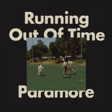 On a black background, top text reading "Running Out of Time" and bottom text reading "Paramore". In the foreground, partially covering the text, a photograph of two people on an astroturf field with trees in the background run towards another person.